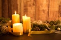 The warmth of the Christmas concept: three candles lit on a dark wooden table and a rustic wooden setting with pine branches, Royalty Free Stock Photo