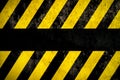 Warning background with yellow and dark stripes painted over concrete wall facade texture and empty space for text message in the