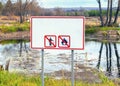 Warning banner on the shore of the pond with inscriptions prohibiting Smoking and bonfire in nature without text.