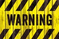 WARNING danger sign word text as stencil with yellow and black stripes painted on wood wall plank texture wide background