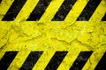 Warning danger sign yellow and black stripes pattern with yellow area over concrete cement wall facade peeling cracked Danger sign