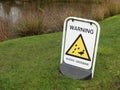 Warning ducks crossing sign beside village pond Royalty Free Stock Photo
