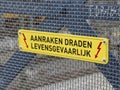 Warning on fence above electricity cables for trains that touching is life-threatening aanraken dragen levensgevaarlijk in the