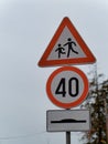 Warning pedestrian crossing sign, round speed limit 40 sign, andhump sign on a pole