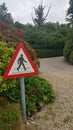 Warning pedestrian sign beside gravel driveway.