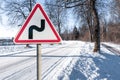 Warning road sign indicating a double bend in wintry conditions Royalty Free Stock Photo
