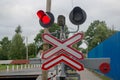 Road sign of railway crossing with double traffic light, shining red indicating approaching train, sound speakers, barrier lowered Royalty Free Stock Photo