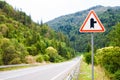 Warning road sign SIDE ROAD AHEAD RIGHT in red triangle on mountain highway Royalty Free Stock Photo