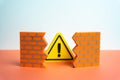 A warning sign bursts through a hole in the wall. A problem that destroys integrity Royalty Free Stock Photo