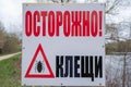 Warning sign Caution ticks in Russian. The concept of biological safety. Royalty Free Stock Photo