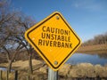 Warning sign `Caution! Unstable riverbank`. Black letters on yellow background