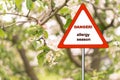 Warning sign: danger allergy season against the background of a blossoming branch of an apple tree Royalty Free Stock Photo