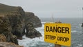 Warning sign Danger Steep Drop at cliffs edge by ocean rocks Royalty Free Stock Photo