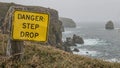 Warning sign Danger Steep Drop at cliffs edge by ocean rocks Royalty Free Stock Photo