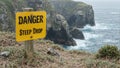 Warning sign Danger Steep Drop at cliffs edge by ocean rocks Royalty Free Stock Photo
