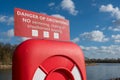 Life-ring rescue equipment seen stationed adjacent to a deep water lake.