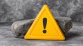 Warning sign with exclamation mark placed on a rock surface for safety alert Royalty Free Stock Photo