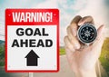 Warning sign goal ahead with hand holding compass Royalty Free Stock Photo