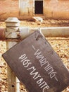 A view of a warning sign at a pig enclose with two pigs in the background Royalty Free Stock Photo