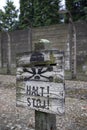 A warning sign placed in front of a barbed wire electric fence at the Auschwitz-Birkenau State Museum in Poland.