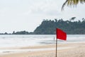 Warning sign of a red flag at a beautiful beach with a blue sky Royalty Free Stock Photo