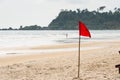 Warning sign of a red flag at a beautiful beach with a blue sky Royalty Free Stock Photo