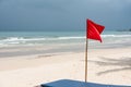 Warning sign of a red flag at a beautiful beach with a blue sky Royalty Free Stock Photo