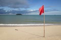 Warning sign of a red flag and shadow of a flag at a beautiful clean beach with a blue sky, cloud and the sea Royalty Free Stock Photo