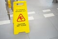 Warning sign with Russian text caution wet floor. A sign near the steps in an office or entertainment center. Cleaning ceramic