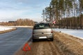 Warning sign stands nearby, dirty gray car breaks down on a road curve in the forest in winter Royalty Free Stock Photo