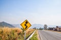 Warning sign - The yellow traffic sign is on the edge of the road to alert the driver that the road ahead is a winding road Royalty Free Stock Photo