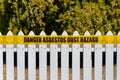 Warning signage about asbestos dust hazard outside a house