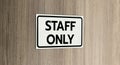 Warning silver stainless steel sign with character black message staff only in front of the wooden door Royalty Free Stock Photo