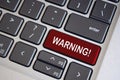 Warning text on dark red laptop keyboard. Security and warning concept