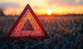Warning triangle at sunset in a field signaling caution and road safety Royalty Free Stock Photo