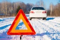 Warning triangle and white car on winter country road, foc Royalty Free Stock Photo