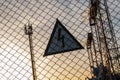 Warning triangular sign with a lightning image on the net fence. Dangerous - high voltage. Electrical substation