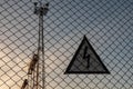 Warning triangular sign with lightning symbol on the fence. Life threatening. High voltage electrical substation
