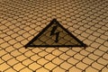 Warning triangular sign with lightning symbol on the fence. Life threatening. No entry. High voltage concept. Sunset Royalty Free Stock Photo