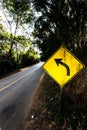 Warning turn left traffic sign along the woodland road Royalty Free Stock Photo