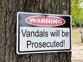 Warning Vandals will be Prosecuted sign on a tree