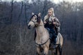 Warrior viking blonde female riding a horse in the woods - Medieval movie scene - Focus on the rider Royalty Free Stock Photo