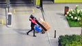 Delivery man pushes hand truck trolley full of cardboards.