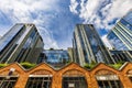 Tall glass corporate buildings facing a small brick arcade of small shops