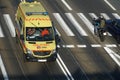 Yellow ambulance with flashing lights on rushing on tram track to bypass traffic jam.