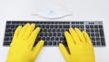 Warsaw, Poland - March 21, 2020:Dell Premier KM717 Black / Gray BT.A man in bright yellow rubber gloves is typing on the keyboard.