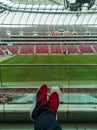 Alone man with black trousers and red sneakers sitting at tribune of polish national stadium PGE