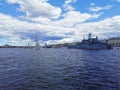 Warships and sailboats in the waters of the Neva River for the Day of the Navy in St. Petersburg against the background of the