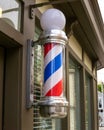 Warwick, NY / United States - Sept. 26, 2020: Vertical closeup of a weathered traditional barber pole in front a barber shop