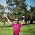 That was the best shot all week. a cheerful young male golfer lifting up his hands in success of playing a good shot Royalty Free Stock Photo